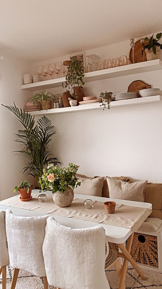 a dining room table with white chairs and plants