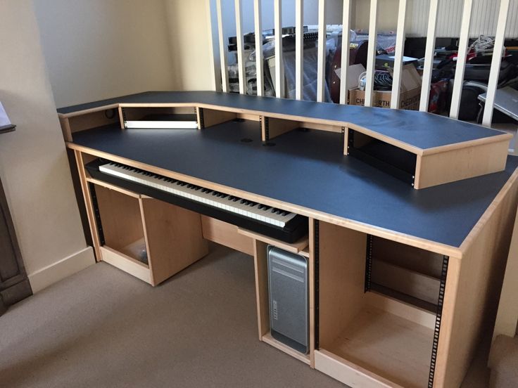 a computer desk with a keyboard on top of it in a room next to a baby crib