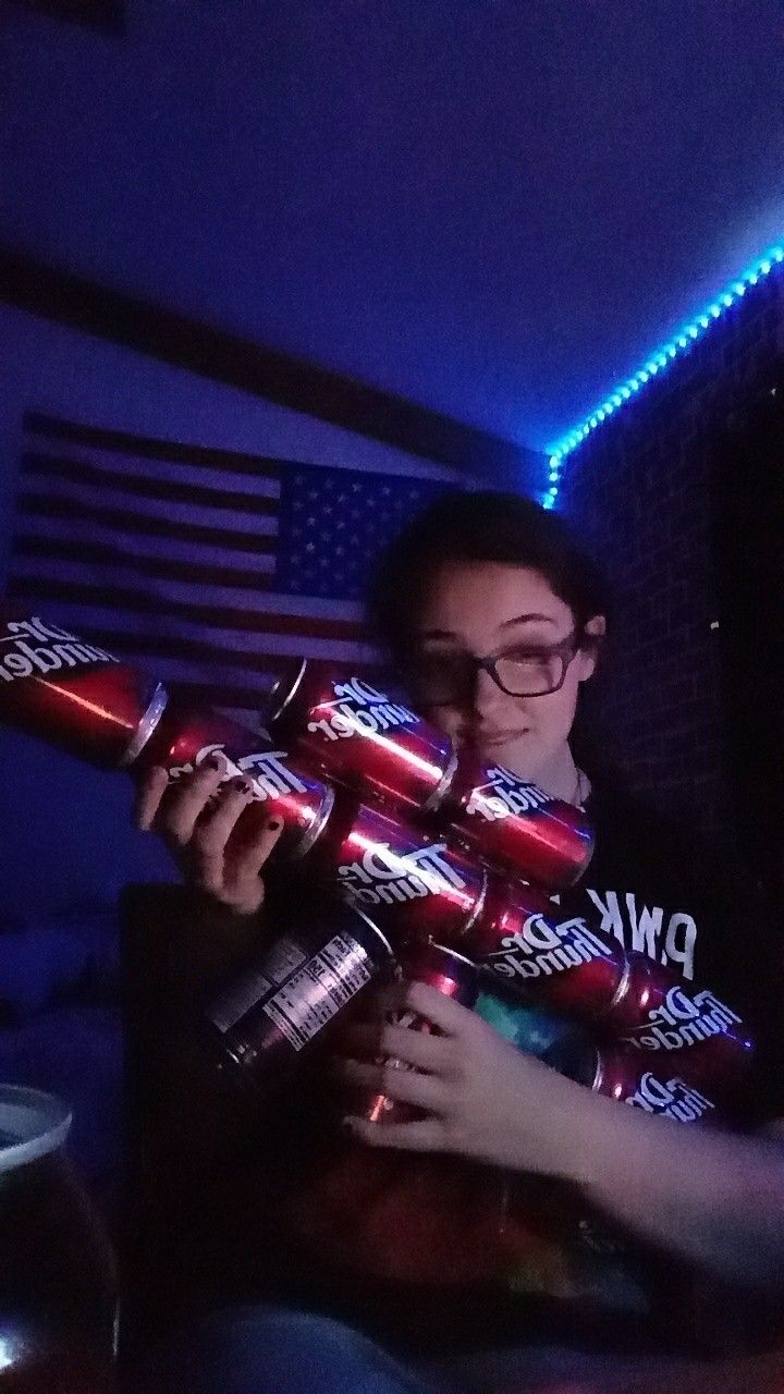 a woman is holding two red and silver objects in front of an american flag on the wall