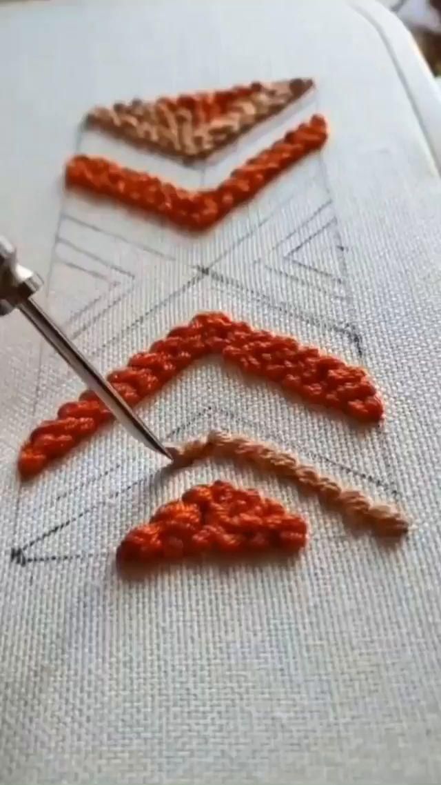 someone is using scissors to thread the stitches on an orange piece of fabric that has been stitched together