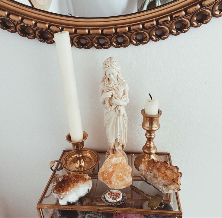 there is a statue and candles on the small table in front of the mirror,