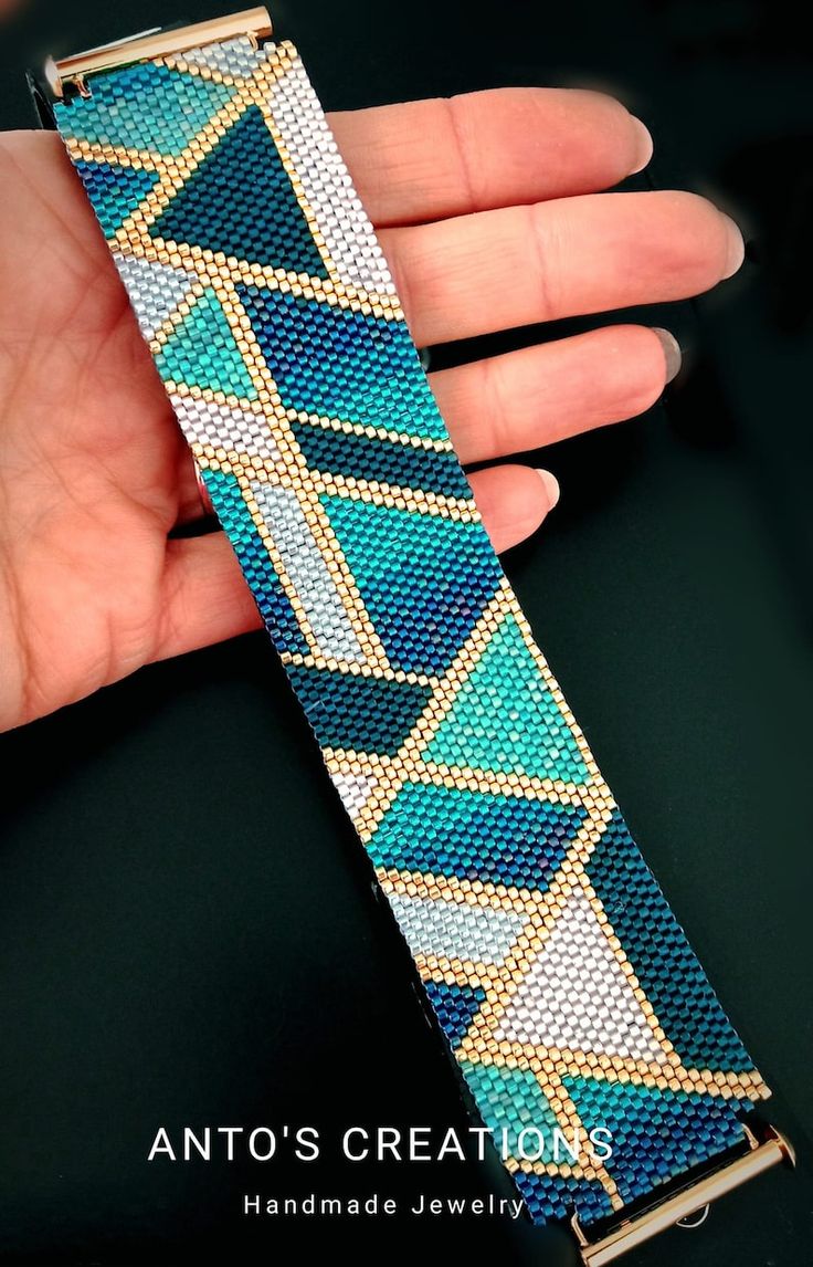 a hand holding a blue and gold watch band with diamonds on it's side