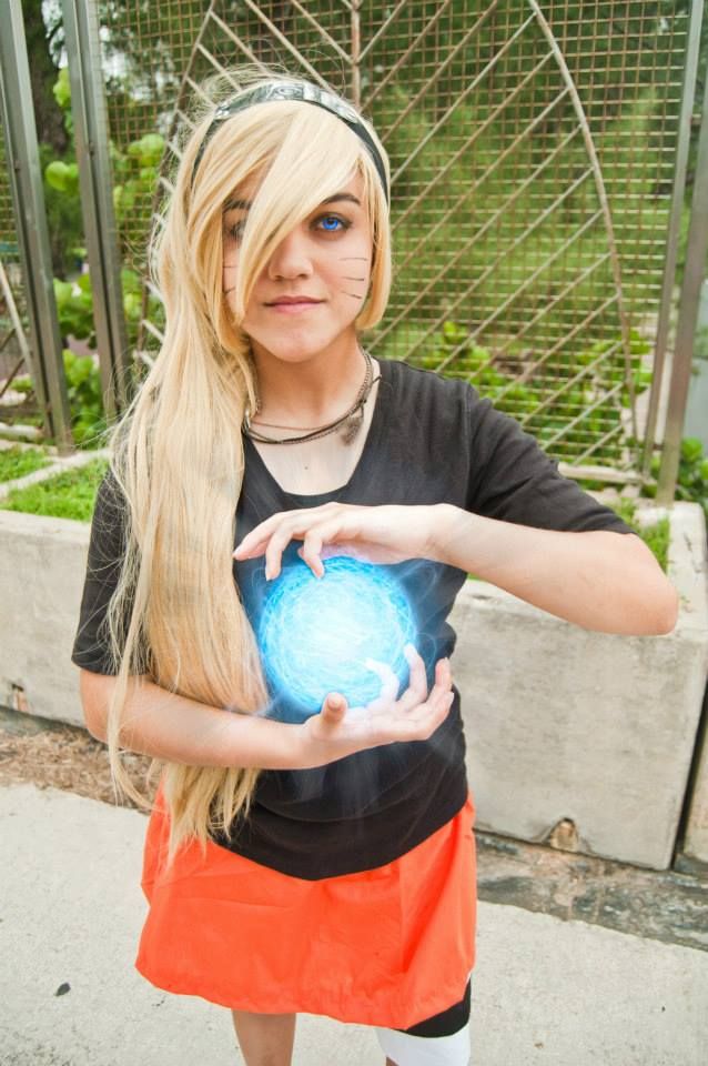 a woman with long blonde hair holding a blue ball in her hands while standing next to a fence