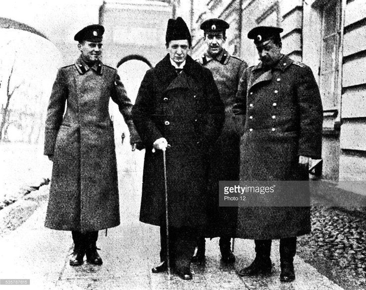 an old black and white photo of four men in uniforms standing on the sidewalk with one man holding a cane