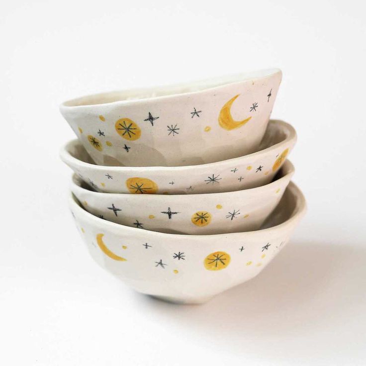 four white bowls with yellow stars and moon designs are stacked on top of each other