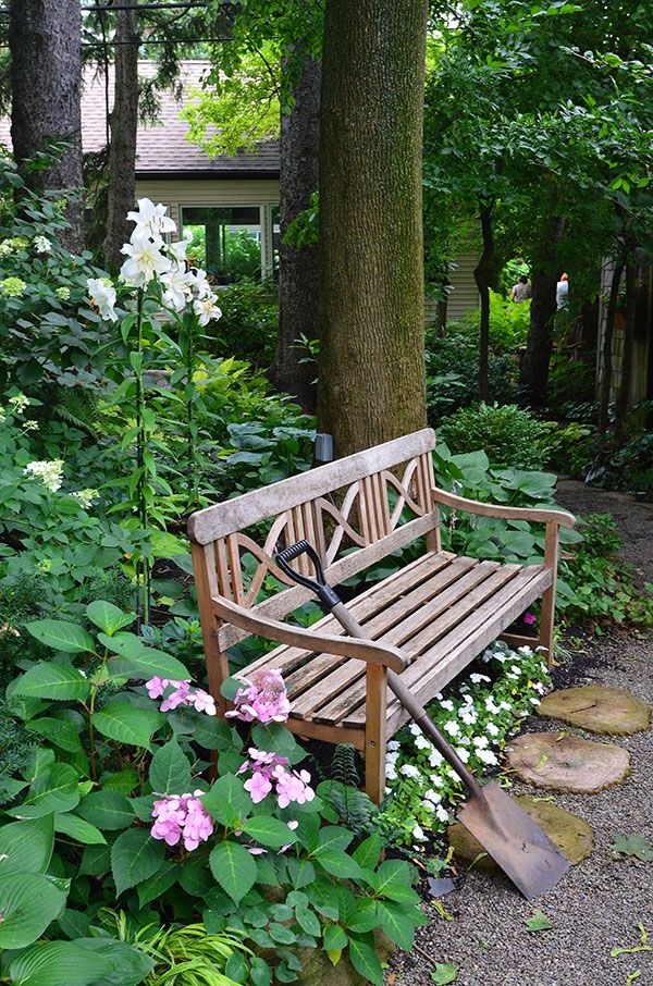 a wooden bench surrounded by flowers and trees