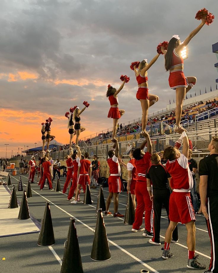 a group of cheerleaders in red and white doing stunts on the sidelines