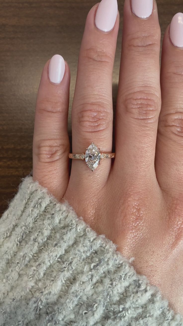 a woman's hand with a ring on it and a white manicured nail