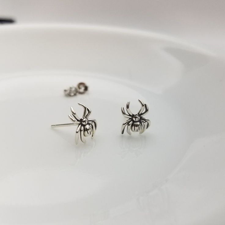 Sterling  Silver Spider Earrings These Halloween themed sterling silver spider stud earrings perfect for adding a hint of Halloween spirit to your look, the frightful yet delightful design features detailed miniature spider crafted with the quality sterling  silver, ensuring that they will last you through many Spookytacular seasons! Size: approximately 8mm x 10mm Finish: platinum plated on top of the sterling silver. Post size: 22 gauge, 11mm long Sold as a PAIR Comes with gift box Earring back Spider Stud Earrings, Spooky Silver Nickel-free Earrings, Spooky Nickel-free Silver Earrings, Spooky Silver Pierced Earrings, Spooky Silver Dangle Earrings, Halloween Sterling Silver Dangle Earrings, Handmade Sterling Silver Halloween Earrings, Spooky Silver Earrings For Gift, Silver Spooky Halloween Earrings