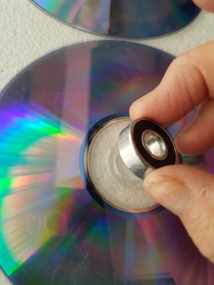 a person is holding a cd in their left hand and pressing the disc with his thumb