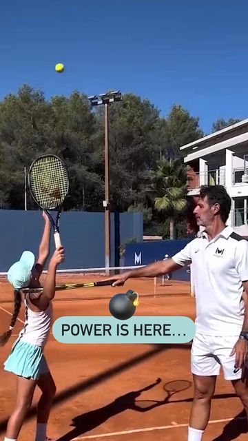 two people on a tennis court with rackets in their hands and one person reaching up to hit the ball