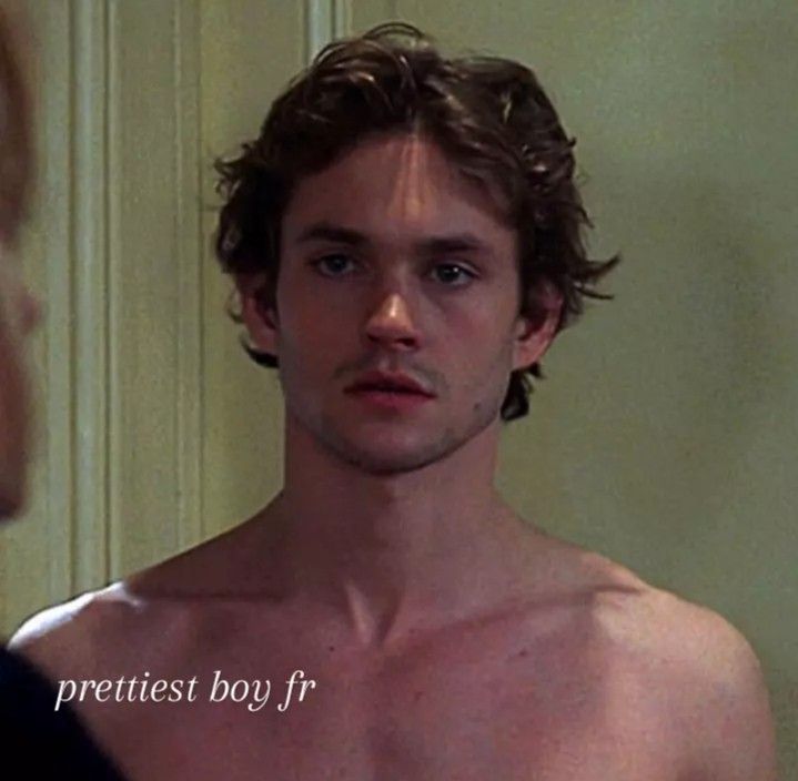 a shirtless young man looking at himself in the mirror with an expression on his face