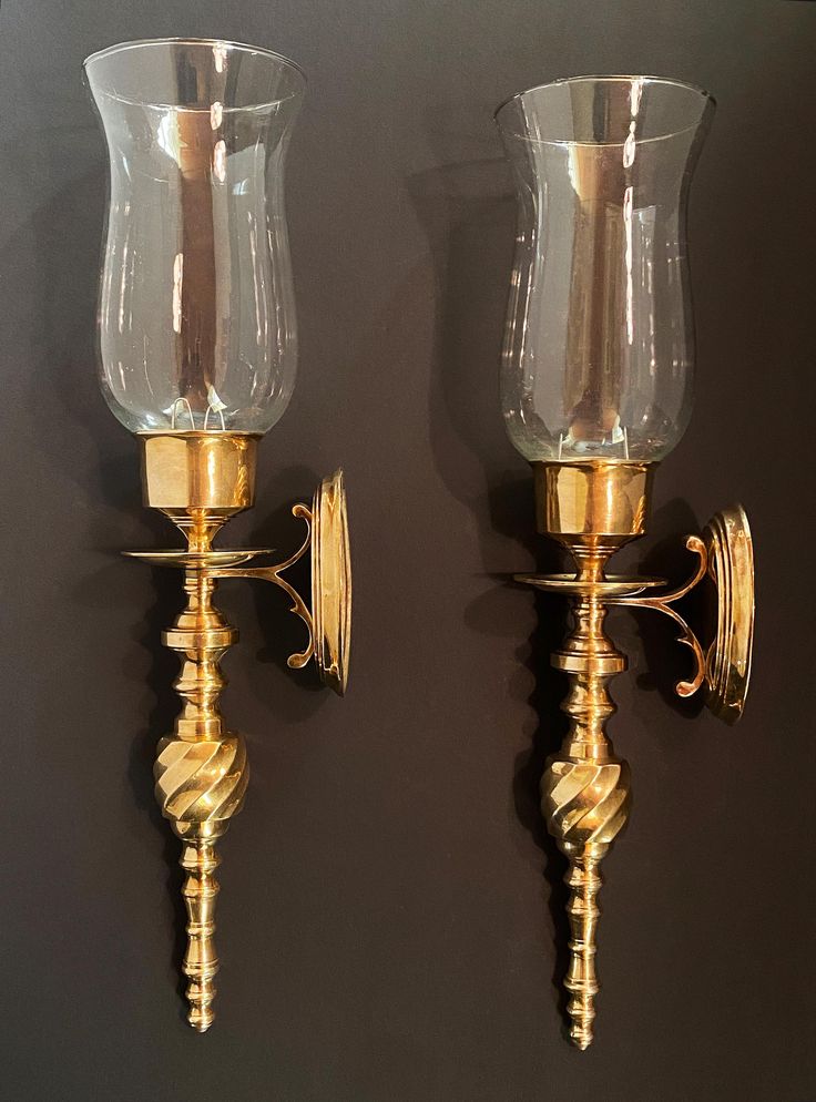 two wall sconces with glass vases attached to them