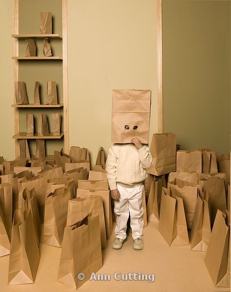 a small child is standing in a room with paper bags on the floor and wearing a bag over his head