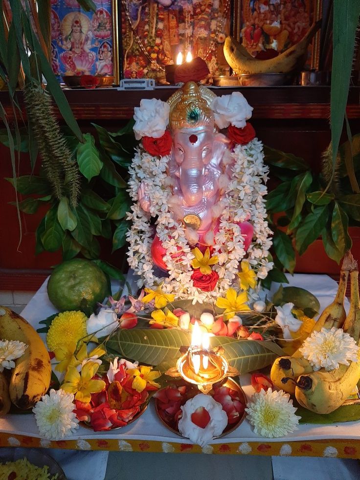 there is a statue with flowers around it and candles in front of the buddha's head