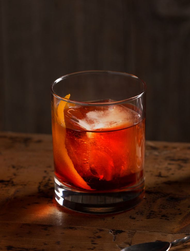 a glass filled with ice and an orange slice sitting on top of a wooden table