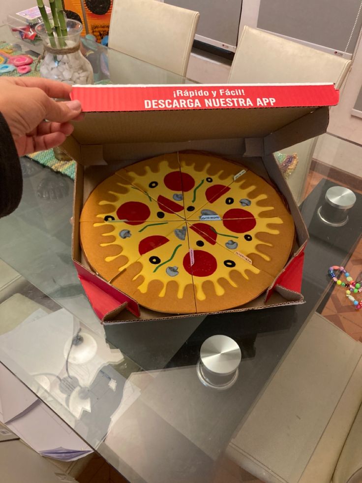 a person holding a pizza in a box on top of a table