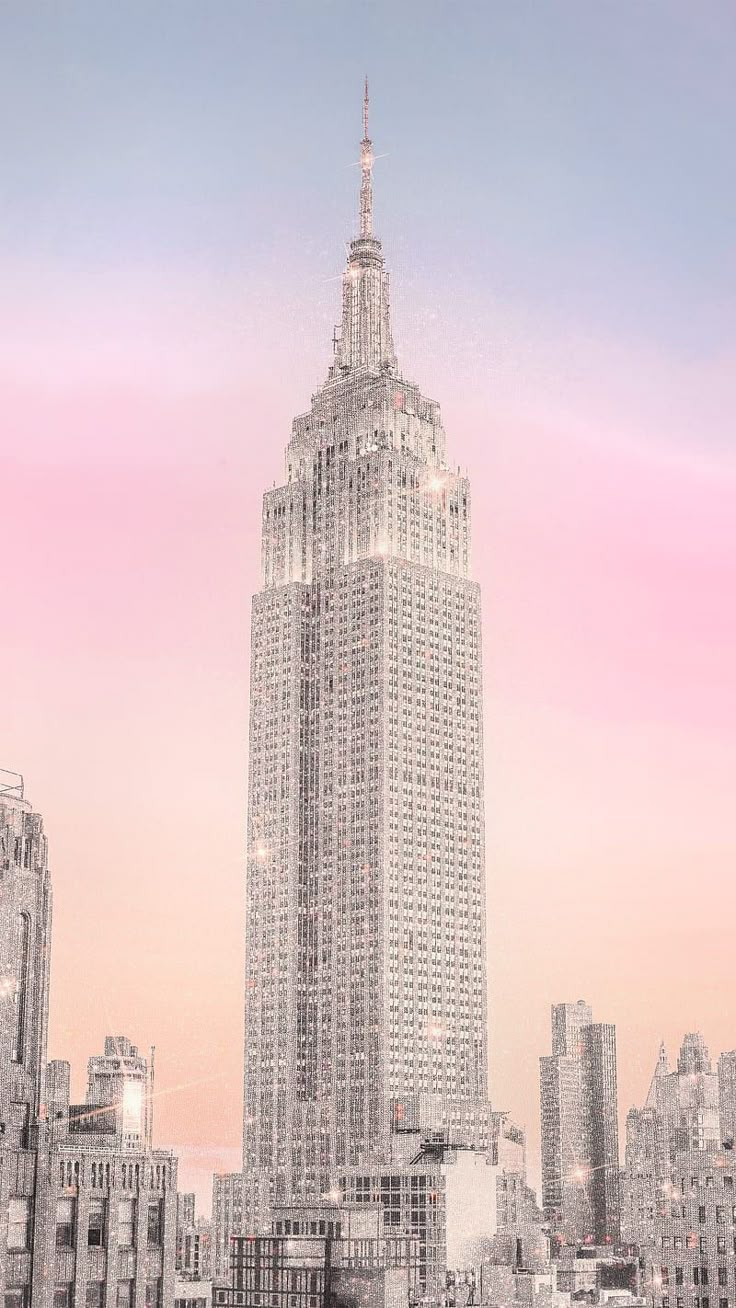 the empire building in new york city is lit up at dusk with pink and blue skies