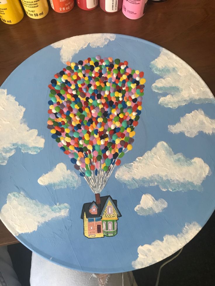 a painted table with a hot air balloon in the shape of a house on it