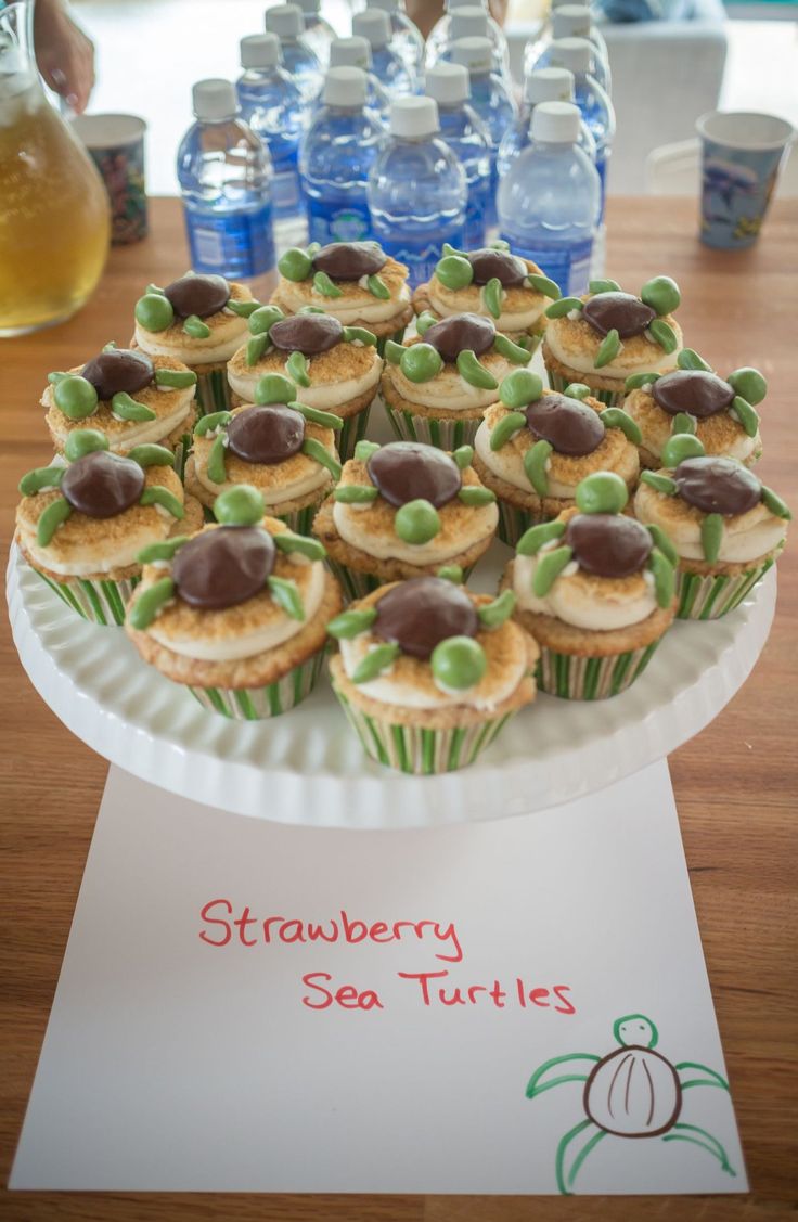 cupcakes are arranged on a paper plate with water bottles in the back ground