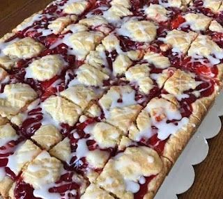 a pie with white icing and strawberries on it sitting on top of a wooden table