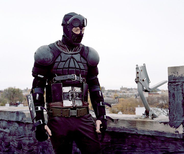 a man dressed in black standing on top of a roof next to a metal object