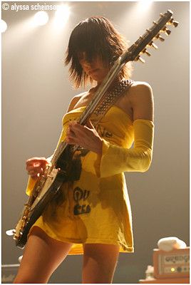 a woman in a yellow dress playing an electric guitar