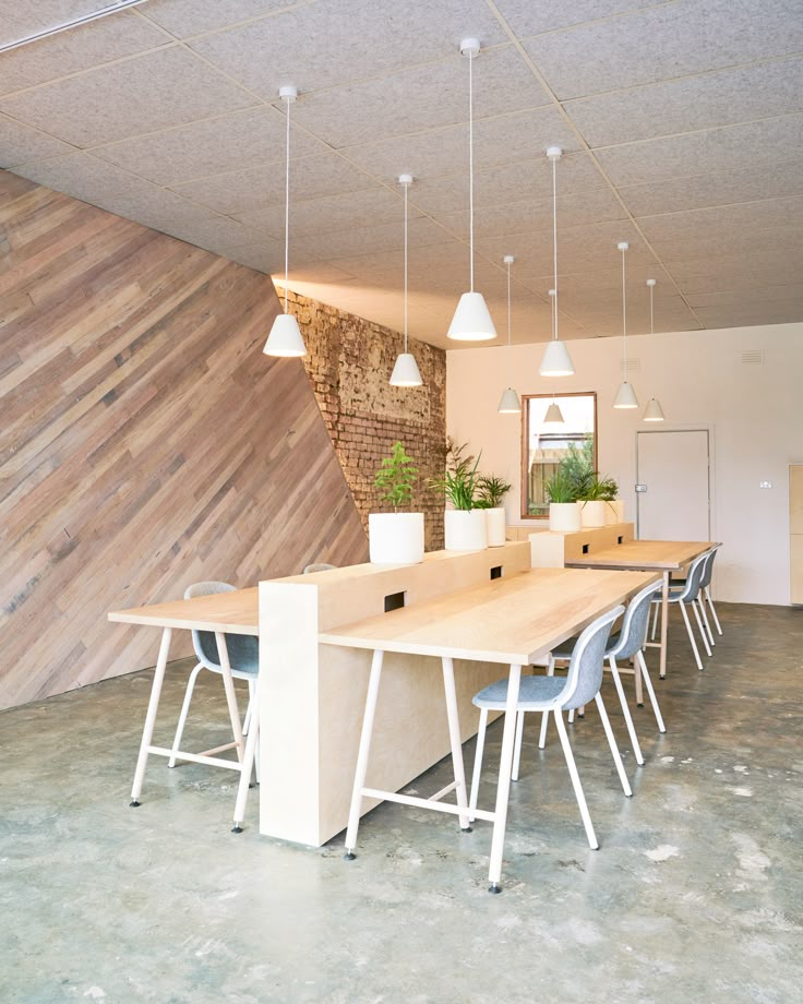 an empty room with several chairs and a table in the center is decorated with wood planks