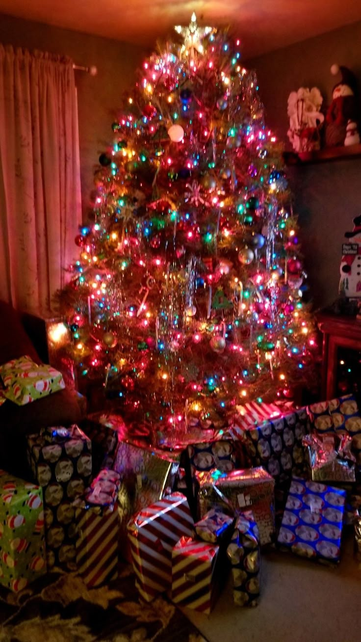 a brightly lit christmas tree with presents under it