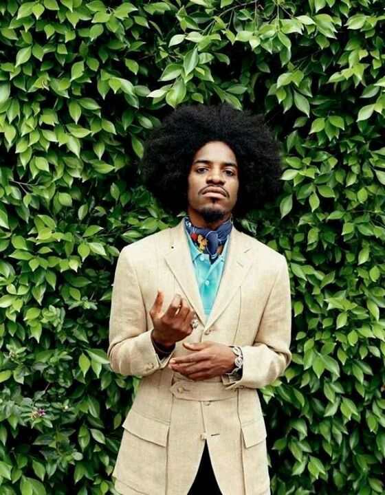 a man with an afro standing in front of a green wall