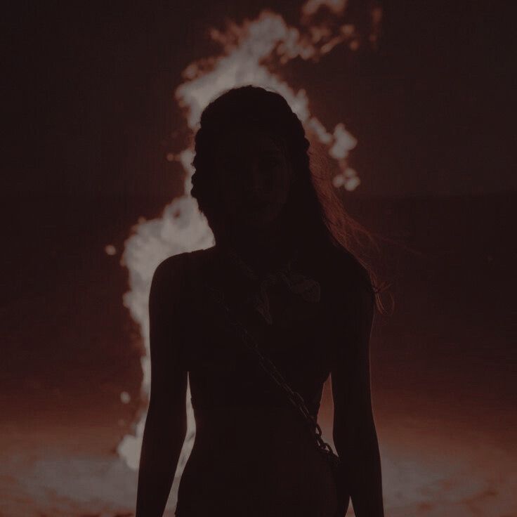 a woman standing in front of a fire