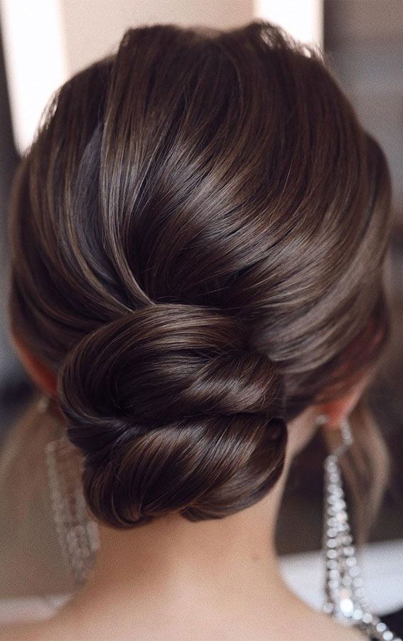 a woman with long hair in a low updo and pearls on her necklaces