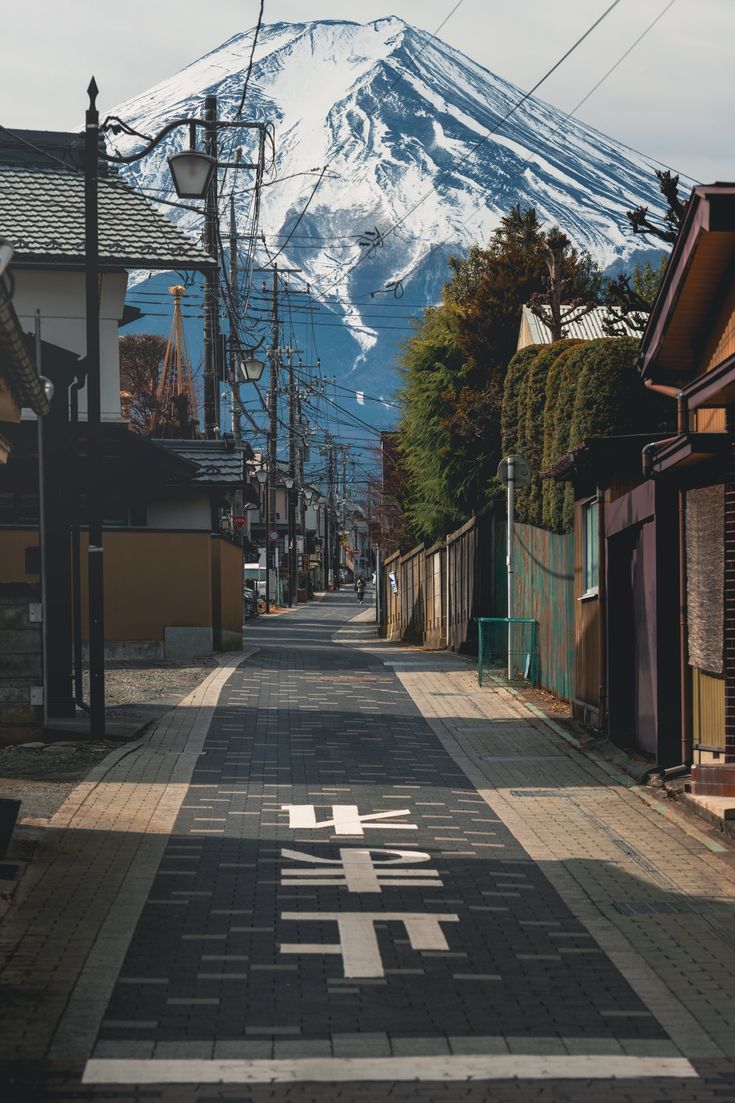 an empty street in front of a snow covered mountain with japanese writing on the pavement