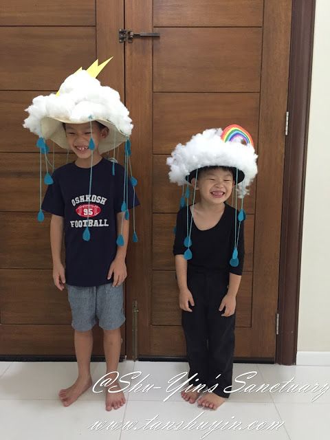 two young boys wearing paper hats made to look like clouds with rainbows on them