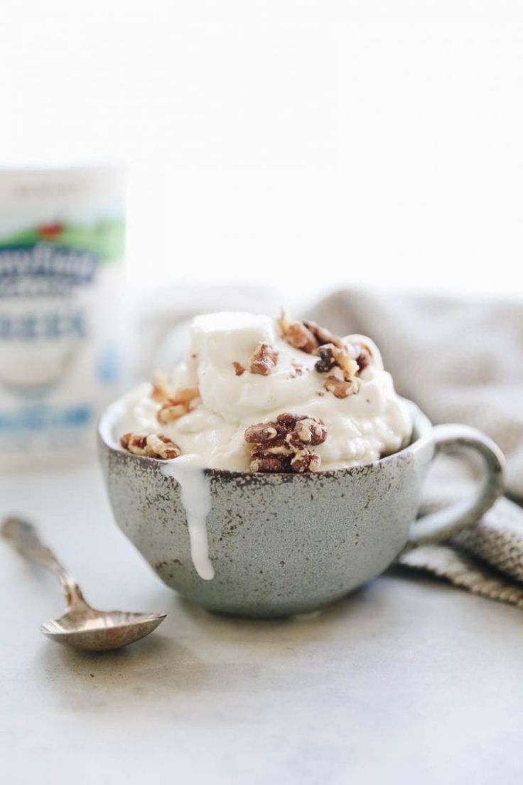 a bowl filled with ice cream and nuts next to a cup of yogurt