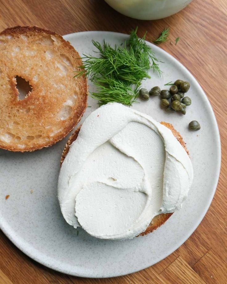 a white plate topped with two bagels covered in cream