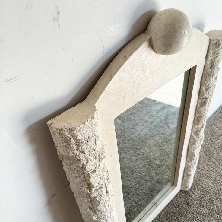 a mirror sitting on the side of a wall next to a carpeted floor and white walls