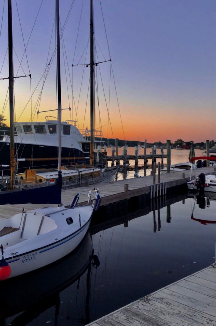 the boats are docked at the dock in the evening time, while the sun is setting