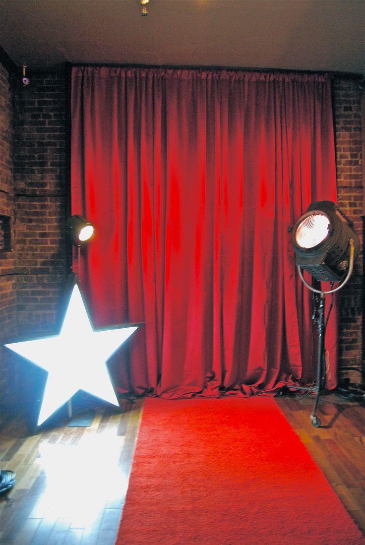 a red curtained room with a white star on the floor and two spotlights