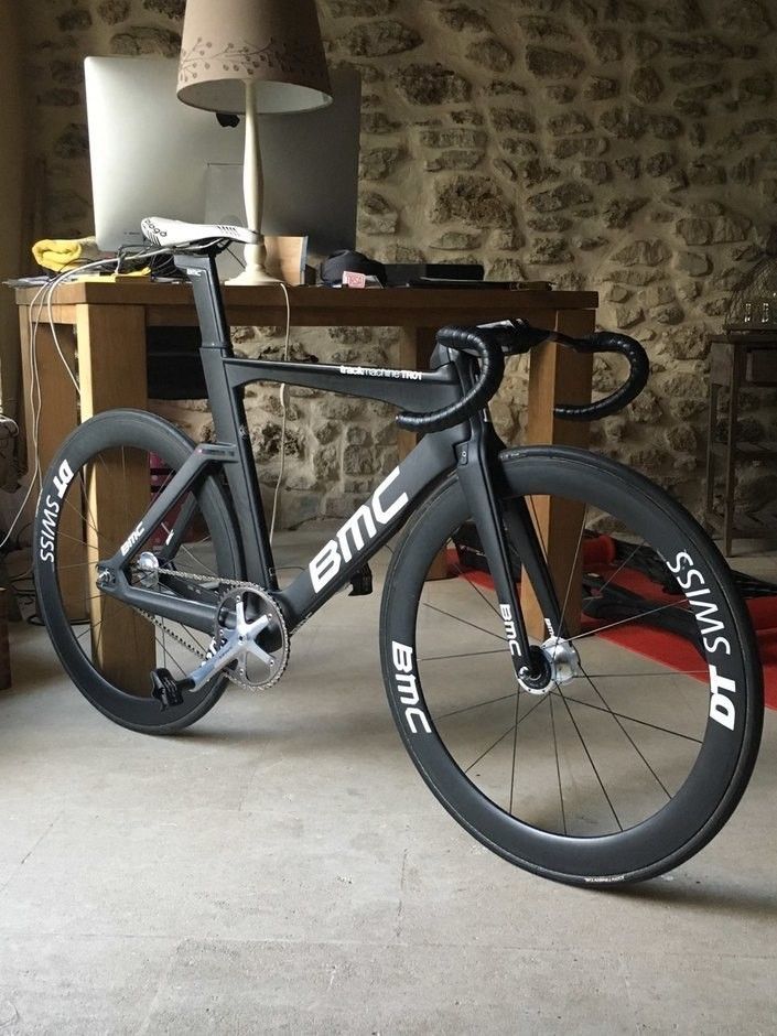 a bike parked in front of a desk with a lamp on it's side