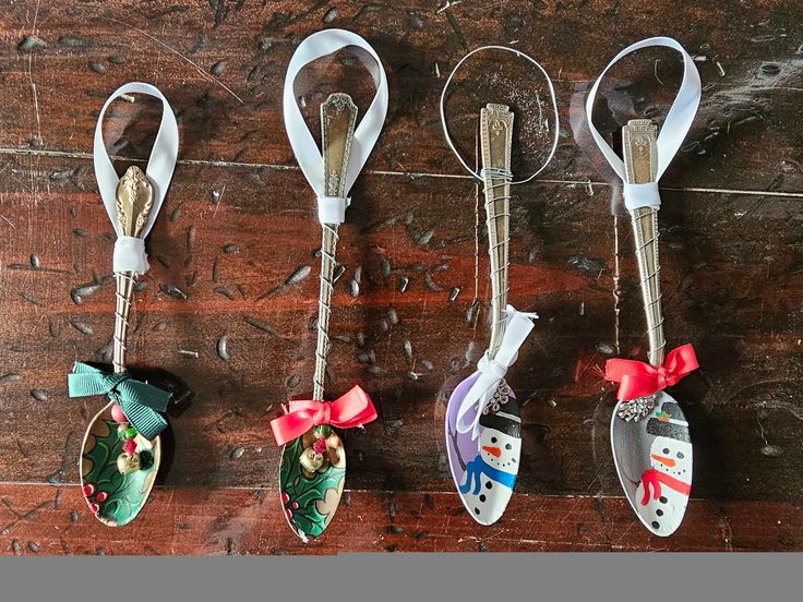 four christmas ornament hanging from hooks on a wooden floor with snowmen and santa hats