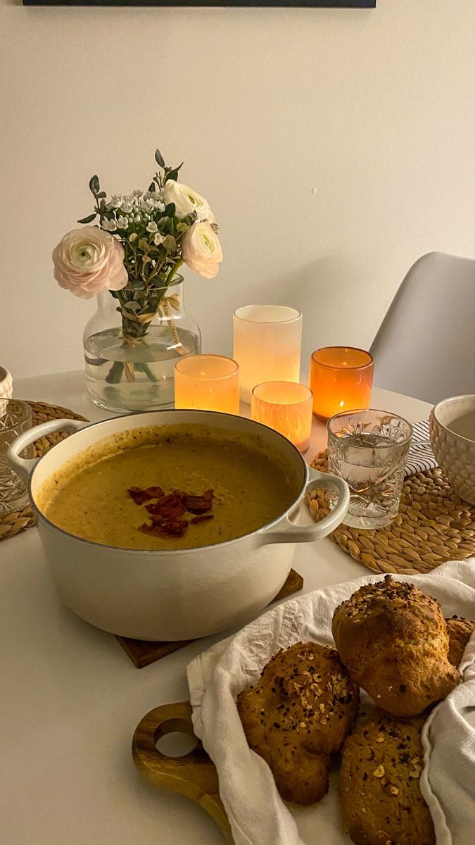 a bowl of soup and some muffins on a table