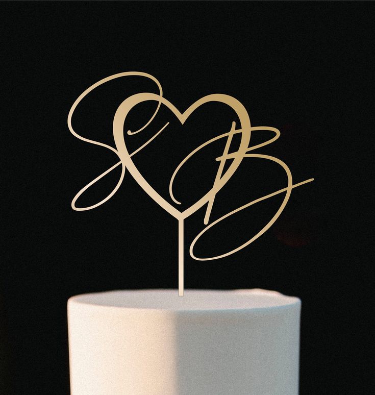 a white cake topped with a heart shaped cake topper next to a black background