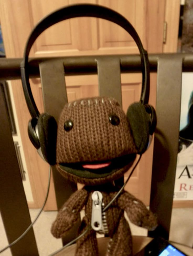 a stuffed animal with headphones on sitting in front of a cell phone and mp3 player