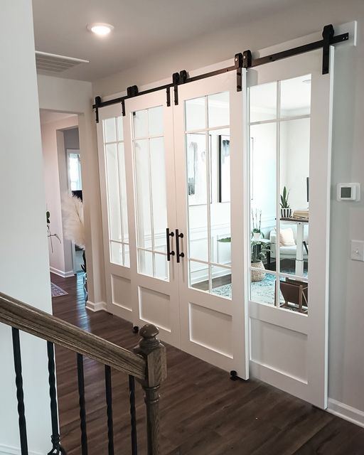 an open door leading to a living room with hardwood floors and white walls, along with glass sliding doors