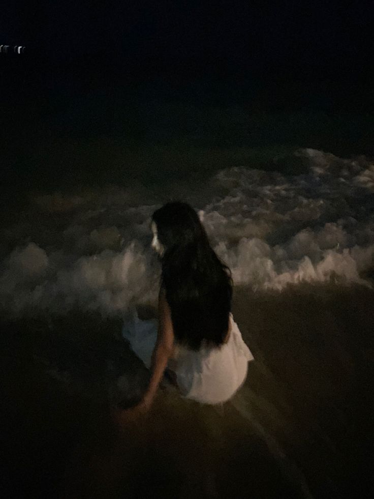 a woman sitting in the ocean at night