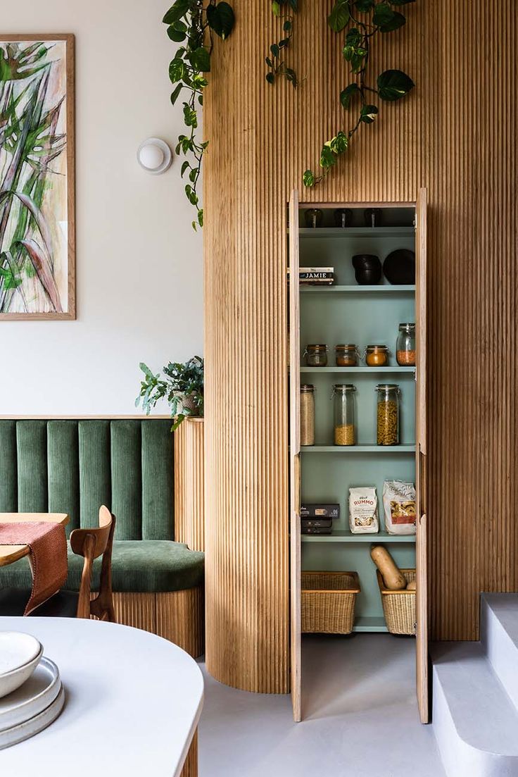 an open shelf in the corner of a room with plants on it and plates, cups, and bowls