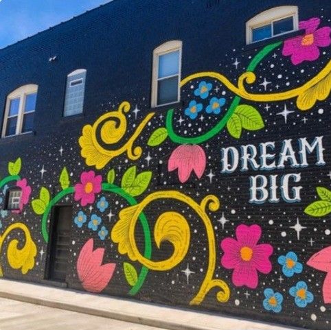 a mural on the side of a building that says dream big with flowers and stars