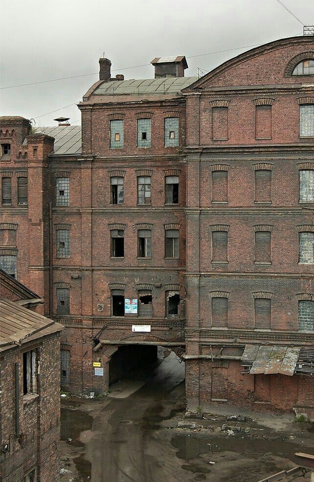 an old brick building with lots of windows next to a tunnel in the middle of it