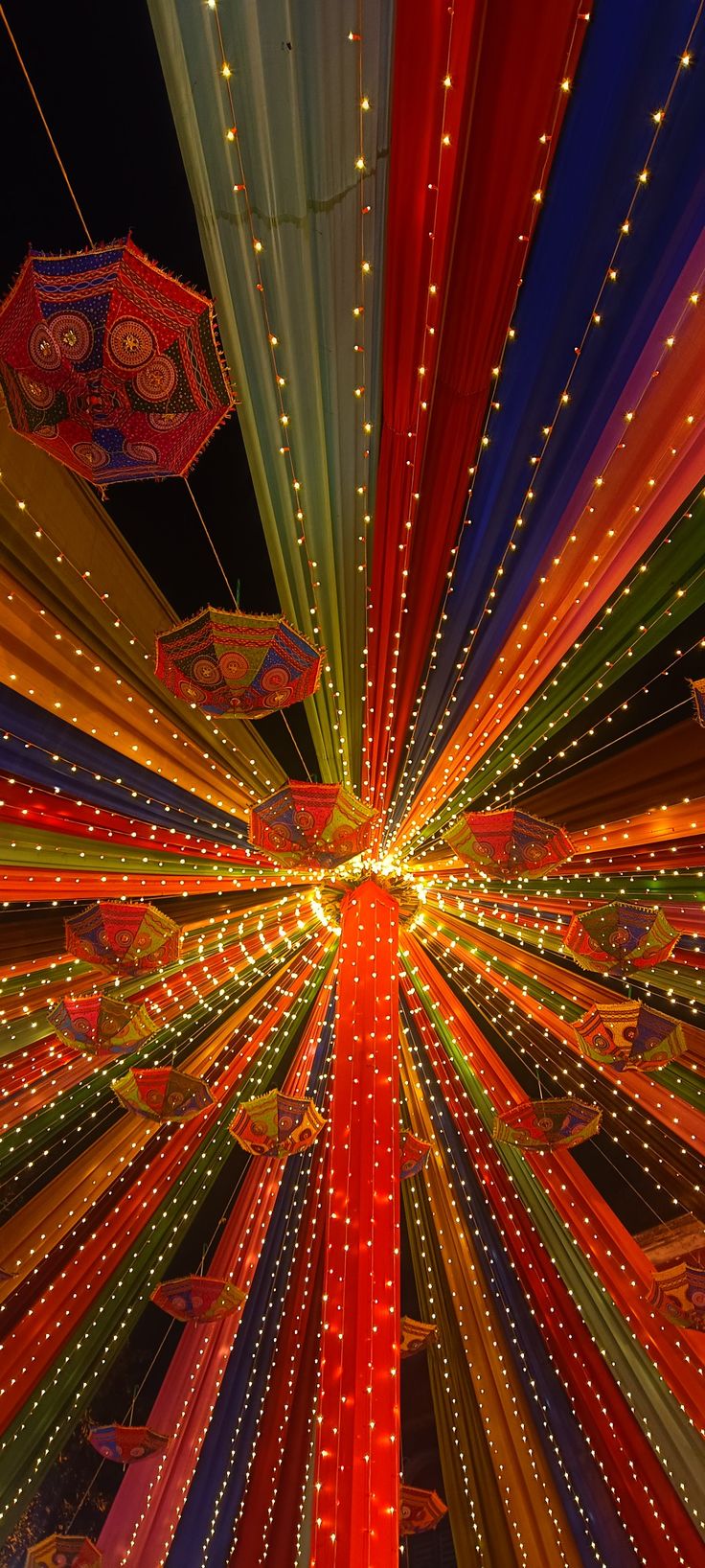 colorful lights and umbrellas are lit up in the night sky at an amusement park